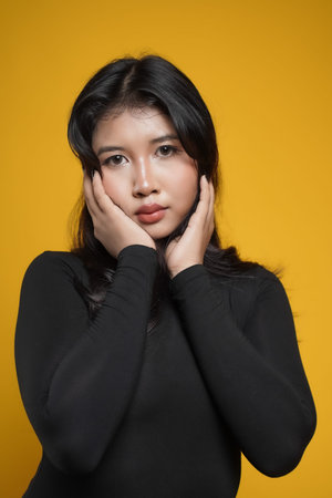 concept photo of beautiful asian woman casual wearing black dress elegant pose isolated on yellow backgroundの写真素材
