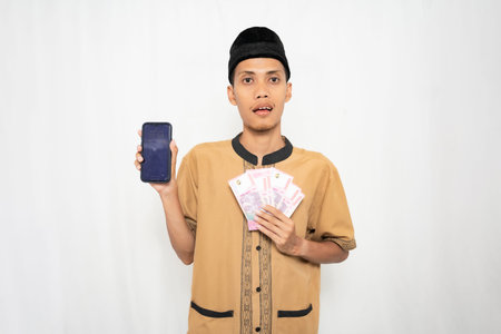 A young man in traditional clothing holding a smartphone and cash