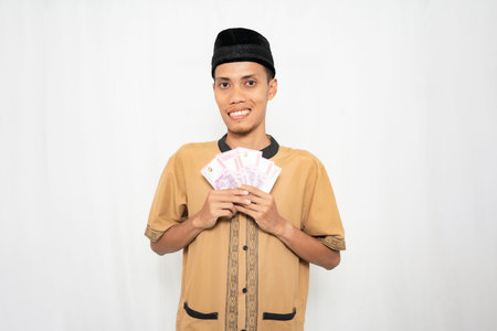 A young man in traditional clothing smiling and holding cash