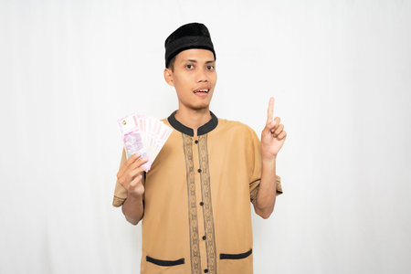 A young man in traditional Asian clothing holding cash and pointing