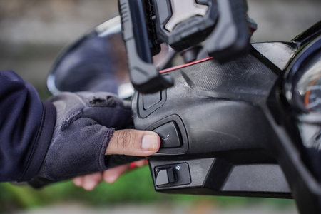 A man's finger presses a motorcycle horn.