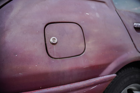 Close-up of a dusty old car gas tank with a silver cap