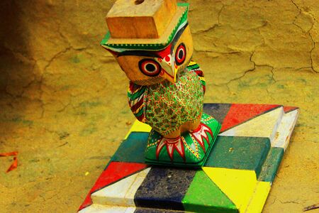 A solo colored owl made of wood standing with a hatの写真素材