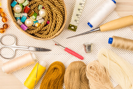 Scissors, buttons, thread, measuring tape and sewing supplies on the cloth and light wooden background. The view from the top.の写真素材