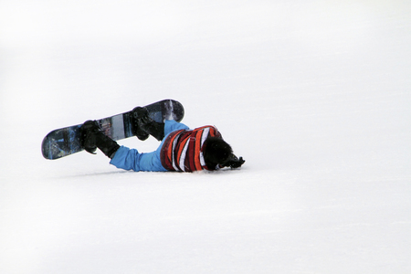 Young man on a snowboard falling on his faceの写真素材