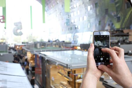 Person taking a photo of a big mall with his smartphoneの写真素材