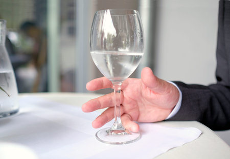 Man reaching for a wineglass filled with water