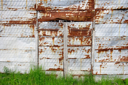 Rusty metal wall with grass at the bottom