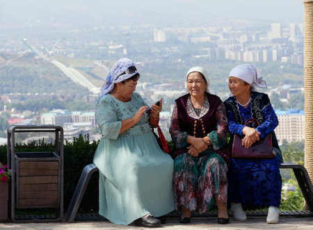 Almaty, Kazakhstan - 3 September 2019: Three senior women are resting on a view point in Almaty while one of them is using her mobile phone.のeditorial素材