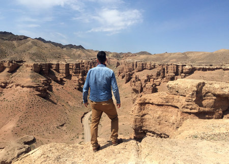 Man in denim shirt overlooking Charyn Canyon in Kazakhstan