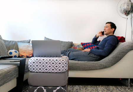 Man working from home with a laptop in the living roomの写真素材