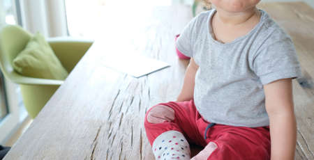 Anonymized view of a baby sitting on a tableの写真素材