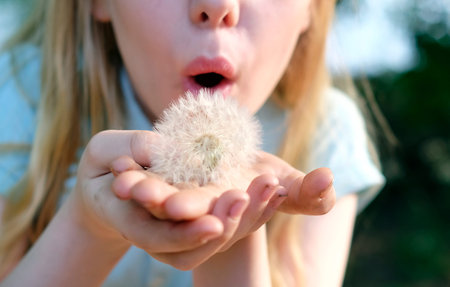 Girl blowing a fluffy dandelion