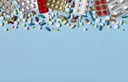 Arrangement of many pills and capsules on blue background
