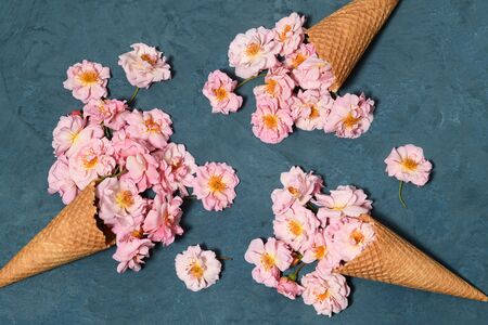 Ice cream cones with small pink roses on blue backgroundの写真素材