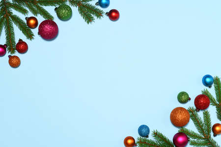 Christmas frame of fir branches and colored baubles on blue backgroundの写真素材