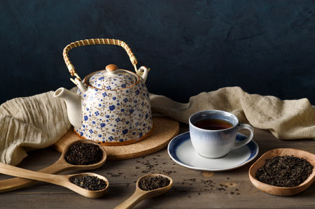 Composition of teapot, cup and assortment of dry tea in wooden spoonsの写真素材
