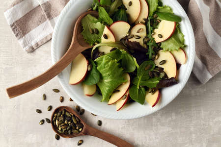 Plate with fresh mix salad of green leaves, apple and pumpkin seedsの写真素材