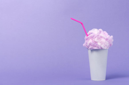 Conceptual image of milkshake with pink foam on viiolet background