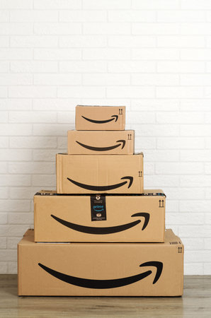 Group of Amazon cardboard boxes on white brick wall background. Bergamo, Italy, 5 march 2021.