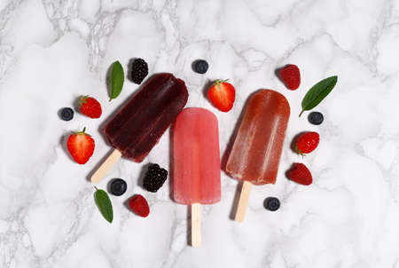 Arrangement of ice pops with berries on marble tableの写真素材