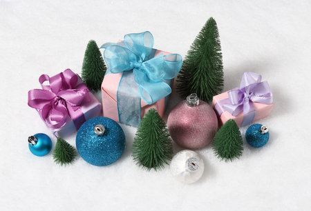 Arrangement of christmas gifts, baubles and trees on snow background