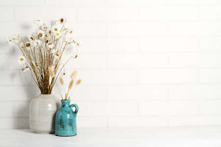 Beautiful bouquets of dry plants against a white brick wallの写真素材