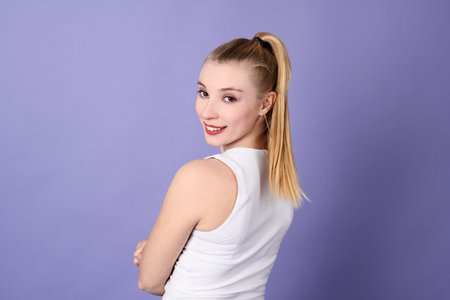 Portrait of beautiful blond young woman on a violet backgroundの写真素材