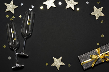 Two flutes with gift and shiny stars on dark backgroundの写真素材