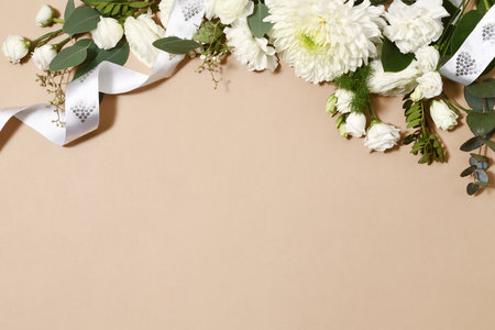 Border of beautiful white flowers with ribbon on beige backgroundの写真素材