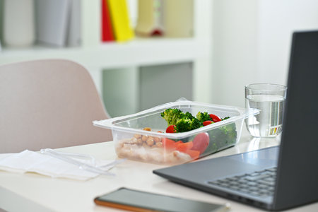 Plastic box with lunch in front of laptop, closeupの写真素材