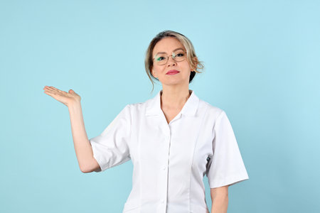 Portrait of cheerful female cosmetologist against light blue backgroundの写真素材