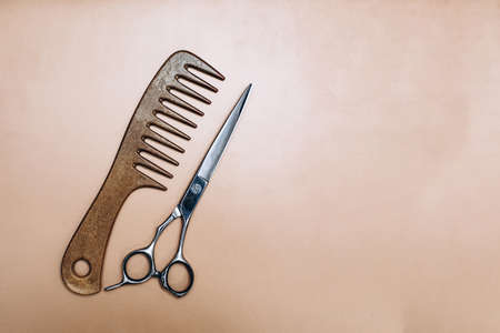 Wooden comb and scissors on a beige background. Hairdressing tools. High quality photoの写真素材