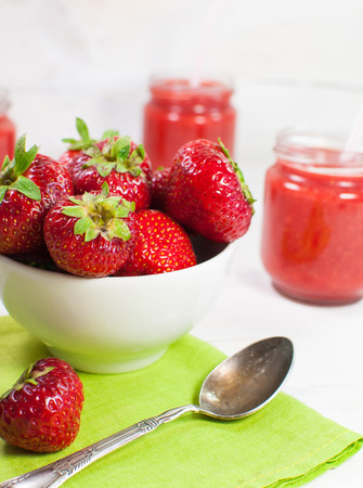 Fresh strawberries in a white bowl. On a white wooden surface.の写真素材