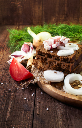 Snack Still Life. Bread with bacon, onion and other greens on a wooden surfaceの写真素材