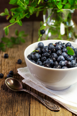 Close-up of blueberries in a white plate on a wooden surfaceの写真素材