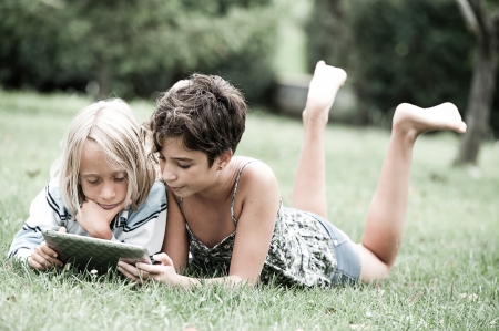 two children lying on the grass looking at something on the tablet,Italyの写真素材