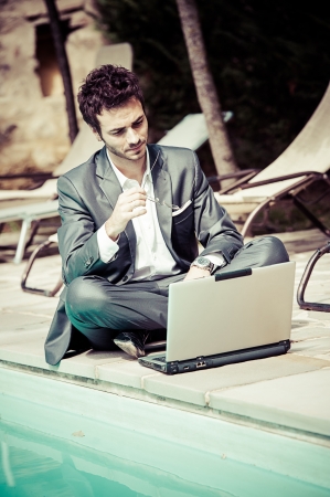 Young Businessman with Computer next to Swimming Pool Italyの写真素材