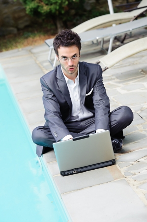 Young Businessman with Computer next to Swimming Pool Italyの写真素材