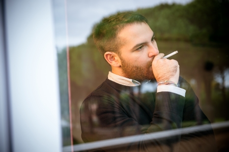 Worried man smoking a cigarette close to the window,Italyの写真素材