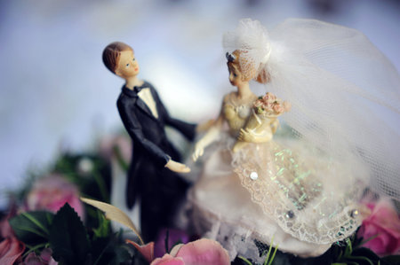 Wedding concept. Bride and fiance. Figurines of the bride and groom on the wedding cake with soft...