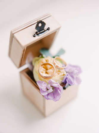 Golden wedding rings lie with flowers in a wooden box. Rustic wedding conceptの写真素材