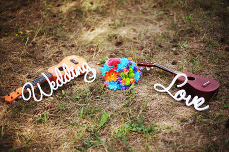 Mexican wedding. Sombrero hat, wedding bouquet, two guitars on the grass. Close up, outdoor. Bright blue, orange, brown, green, purple, beige colors. Country wedding. WEDDING and LOVE letteringの写真素材