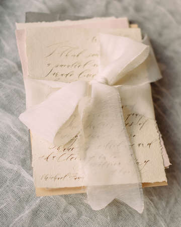 invitation card with handwritten text and white ribbonの写真素材