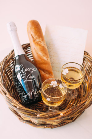 Engagement idea. Romantic picnic for two lovers. Wicker basket with two glasses of champagne, love letter and flowers, fresh baguette and a bottle of champagne. Valentines dayの写真素材