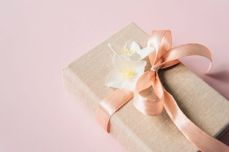 Spring composition with jasmine flowers and gift box on pink table top view. Greeting card for...