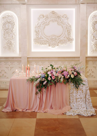 Wedding party. Newlywed's table decorated with tender pink roses, tablecloth, candles and elegant floral composition. Stylish decoration on table.の写真素材
