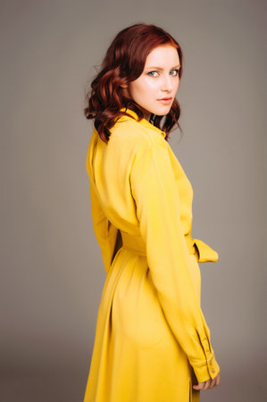 Young ginger woman in yellow shirt dress. Female bright look, lemon casual style. Fashion portrait on neutral studio background.の写真素材