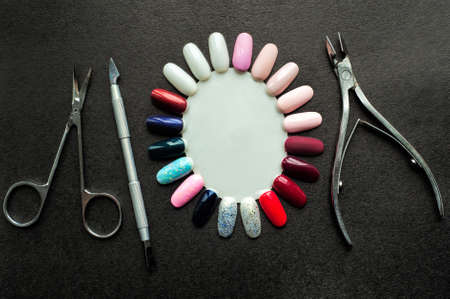 Tools for UV light pedicure. Nail polish layout, Nail Cutter, Cuticle Pusher, Cuticle Nipper, Cuticle Scissors on black background with copy space for designer sign. Top view, macro, closeup.の写真素材