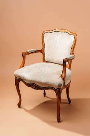 Vintage wooden armchair with armrest and white upholstery on a beige paper backgroundの写真素材